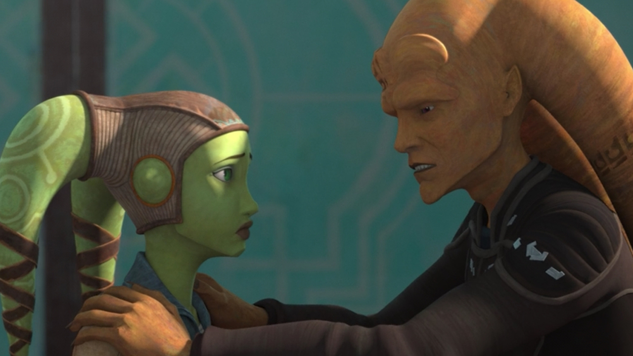 Here we see Hera Syndulla (a green-skinned Twi'lek with two head tails – known as lekku – protruding from the top left and right of her head. She is wearing a brown leather cap, goggles, and a brown leather aviator jacket with a fluffy collar) talking to a taller, older male Twi'lek with orange skin. He looks concerned and has his hands on Hera's shoulders.