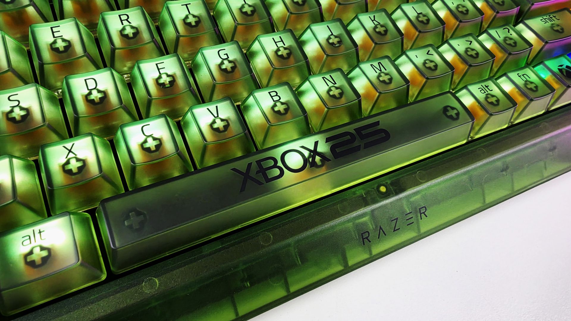 Close-up angled shot of clear smoky-green keycaps and Xbox 25 spacebar on the Razer BlackWidow V4 75% keyboard, showing switch stems beneath.