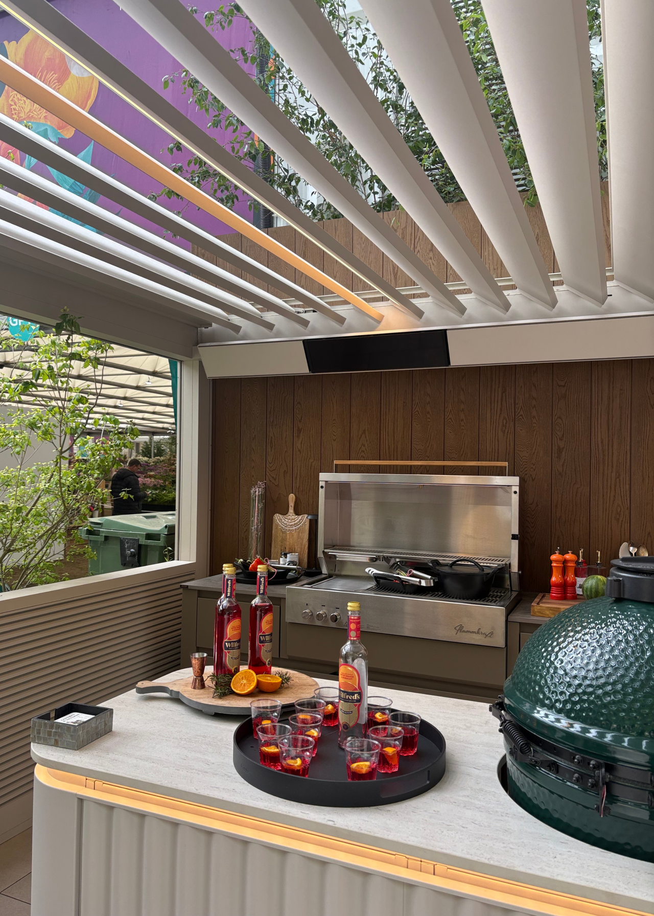 An outdoor kitchen with a stainless steel cooking range, a Big Green Egg, and a tray of Aperols at the Chelsea Flower Show 2026
