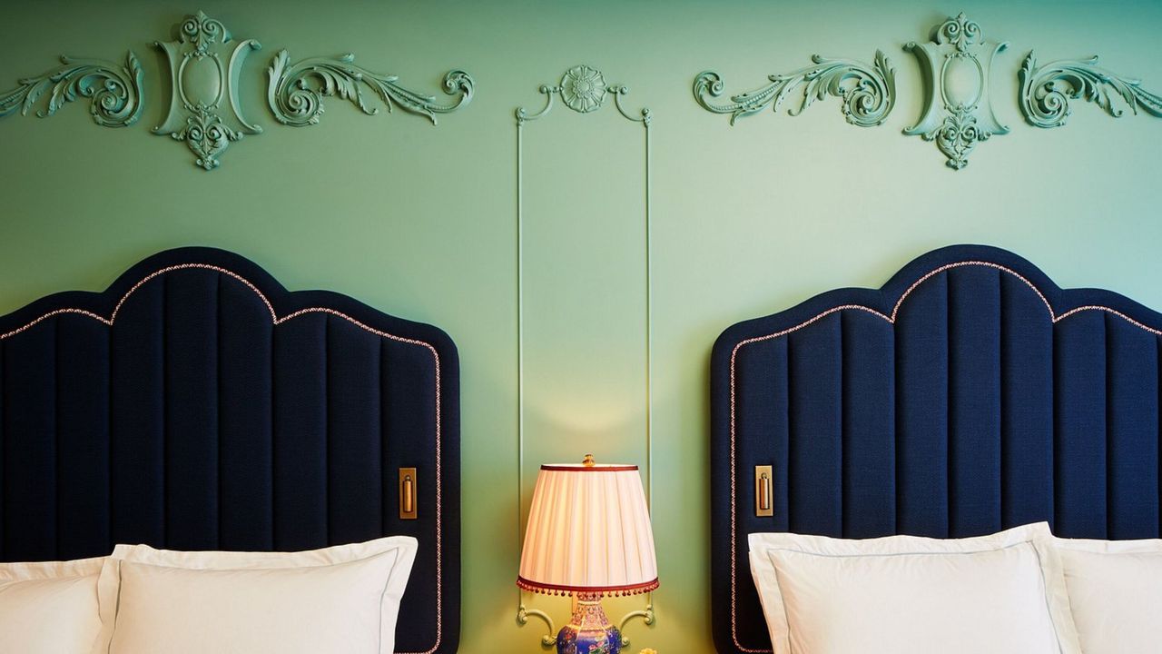 An eccentrically designed modern hotel features a vibrant, pastel-shaded color palette manifesting across multiple wallpaper motifs, upholstery, accent lighting, and Art Deco-inspired furniture.