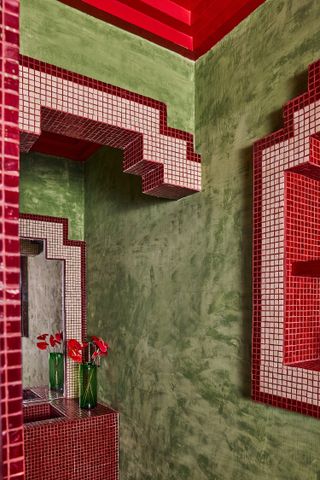 A pistachio green wall with red tile detailing