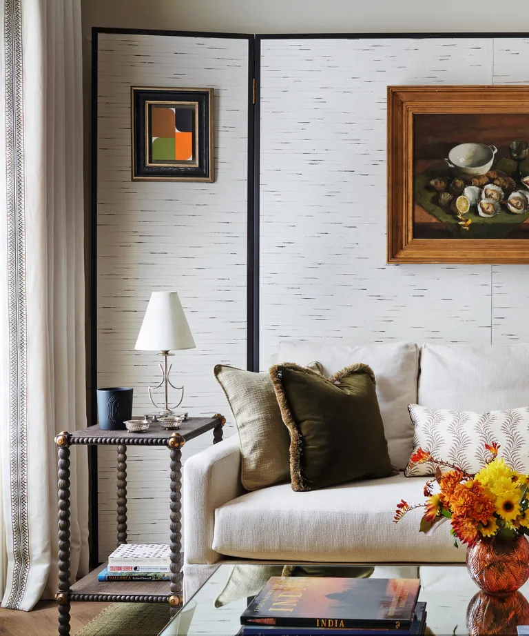 living area with sofa and sidetable with lamp and art on walls with textured wallpaper