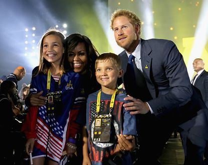 Michelle Obama, Prince Harry, and the children of a service member participating in the Invictus Games.