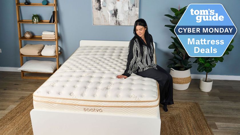 A woman sites on the edge of a Saatva Classic mattress, with a badge overlaid saying Tom's Guide Cyber Monday Mattress Deals