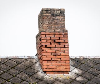 old brick chimney with damage on tiled roof