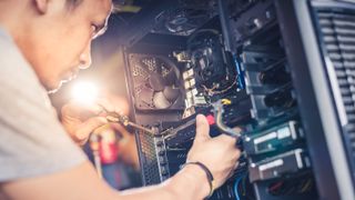 Un homme installe des composants à l'intérieur d'un PC de bureau.