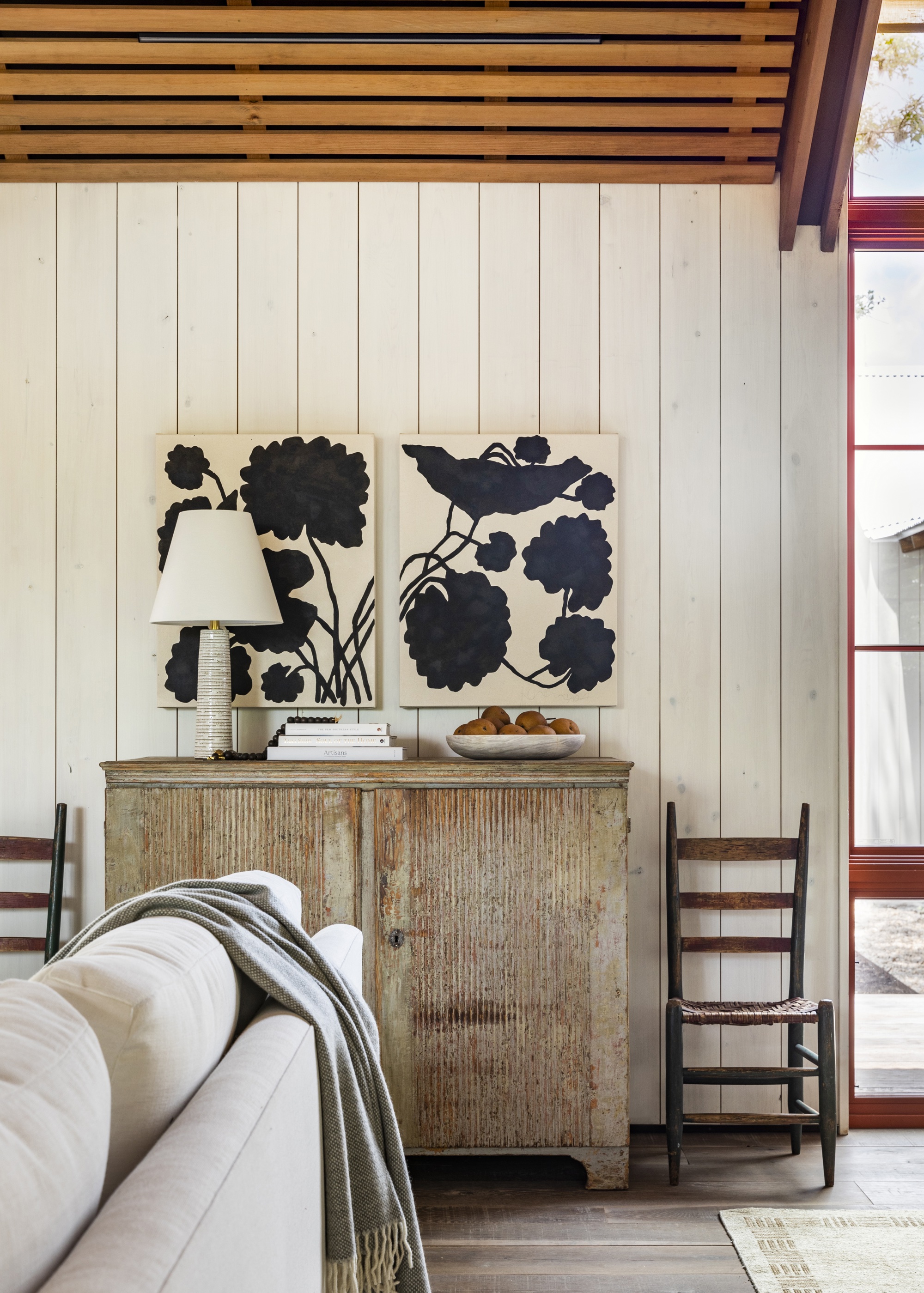 living room with wood clad walls and and antique chest of drawers by Marie Flanigan