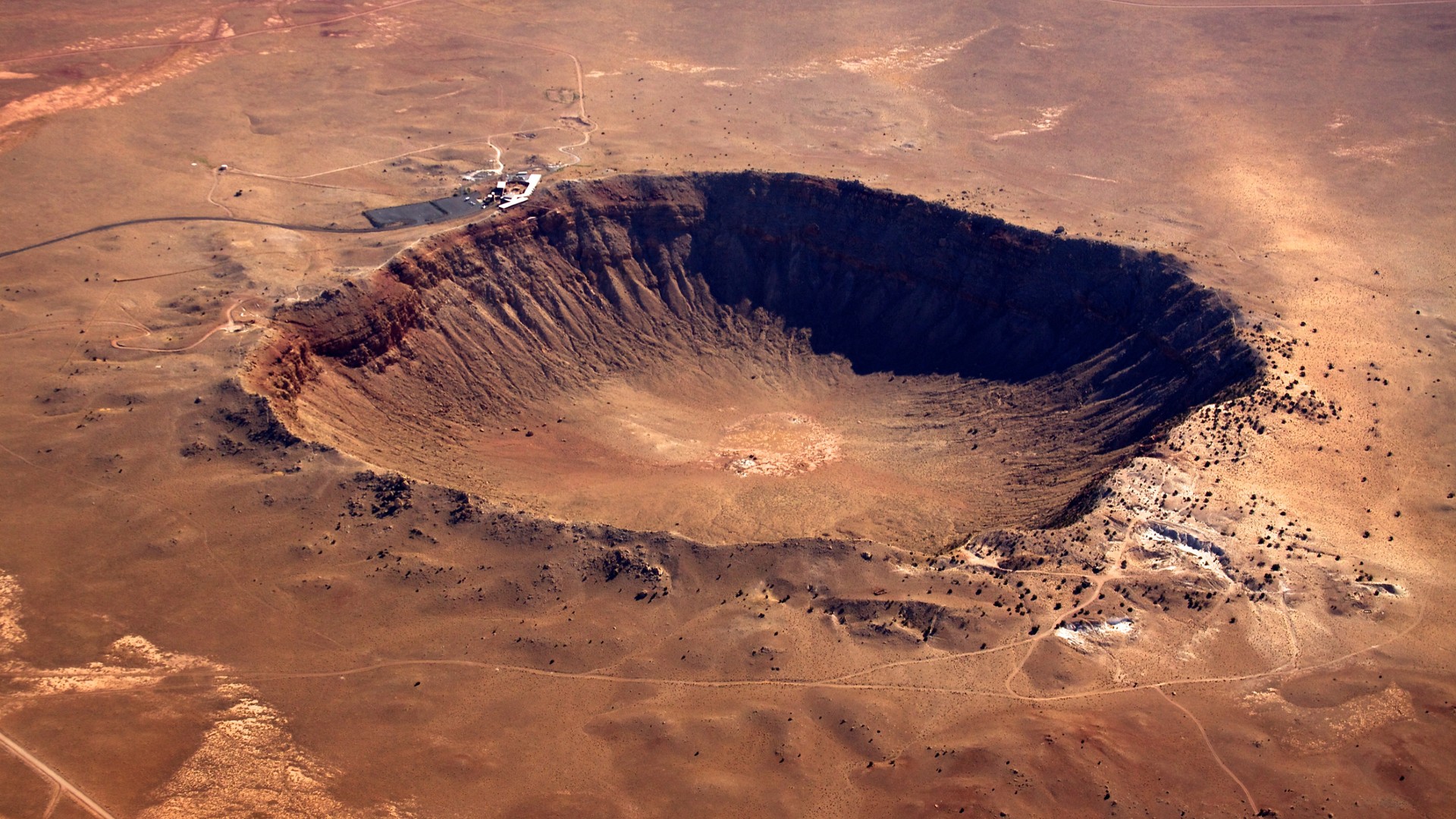 an aerial view of a large, round crater in a desert landscape