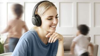 Best headphones under £100: Woman wearing a pair of black Anker Soundcore Q20
