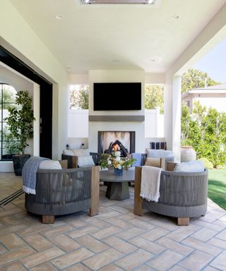 make your home feel like a sanctuary, outdoor living area with four armchairs around a circular coffee table, tv mounted on wall, faux fire, tiled flooring