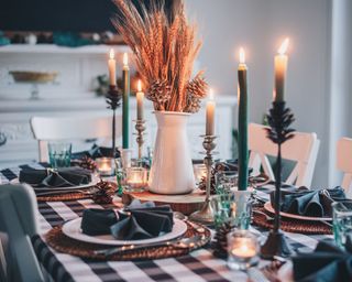 Thanksgiving centerpiece ideas with black and white gingham tablecloth and white jug filled with wheat and pine cones