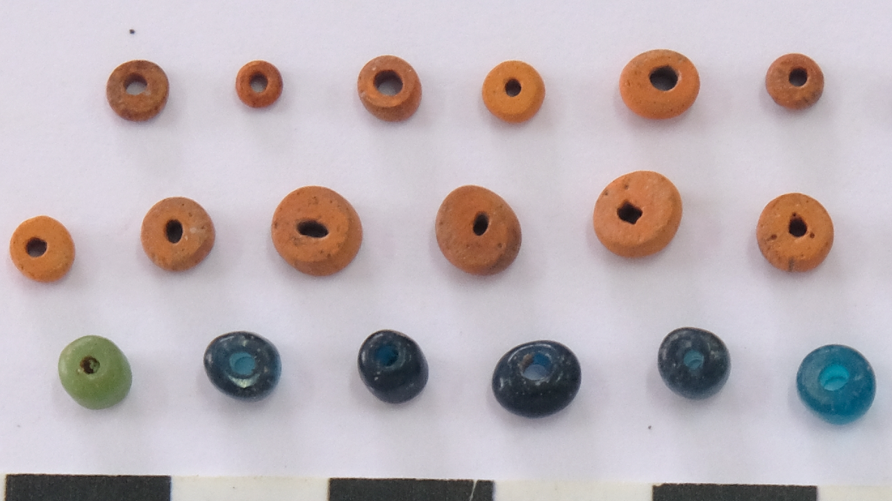 a series of glass beads in orange, green and blue