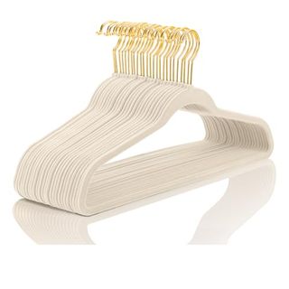 A stack of cream velvet slimline hangars with gold-colored hooks