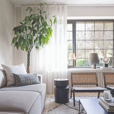 A neutral living room with a grey modular sofa and floor-length voile curtains in white