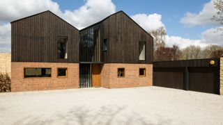 a self build clad with bricks and black timber
