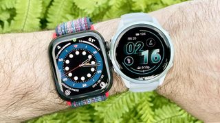 Apple Watch Series 10 next to a Garmin Forerunner 570 on a user's wrist with green foliage out of focus in the background