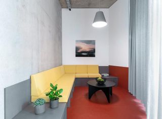 Yellow sofa in an grey office with red carpet