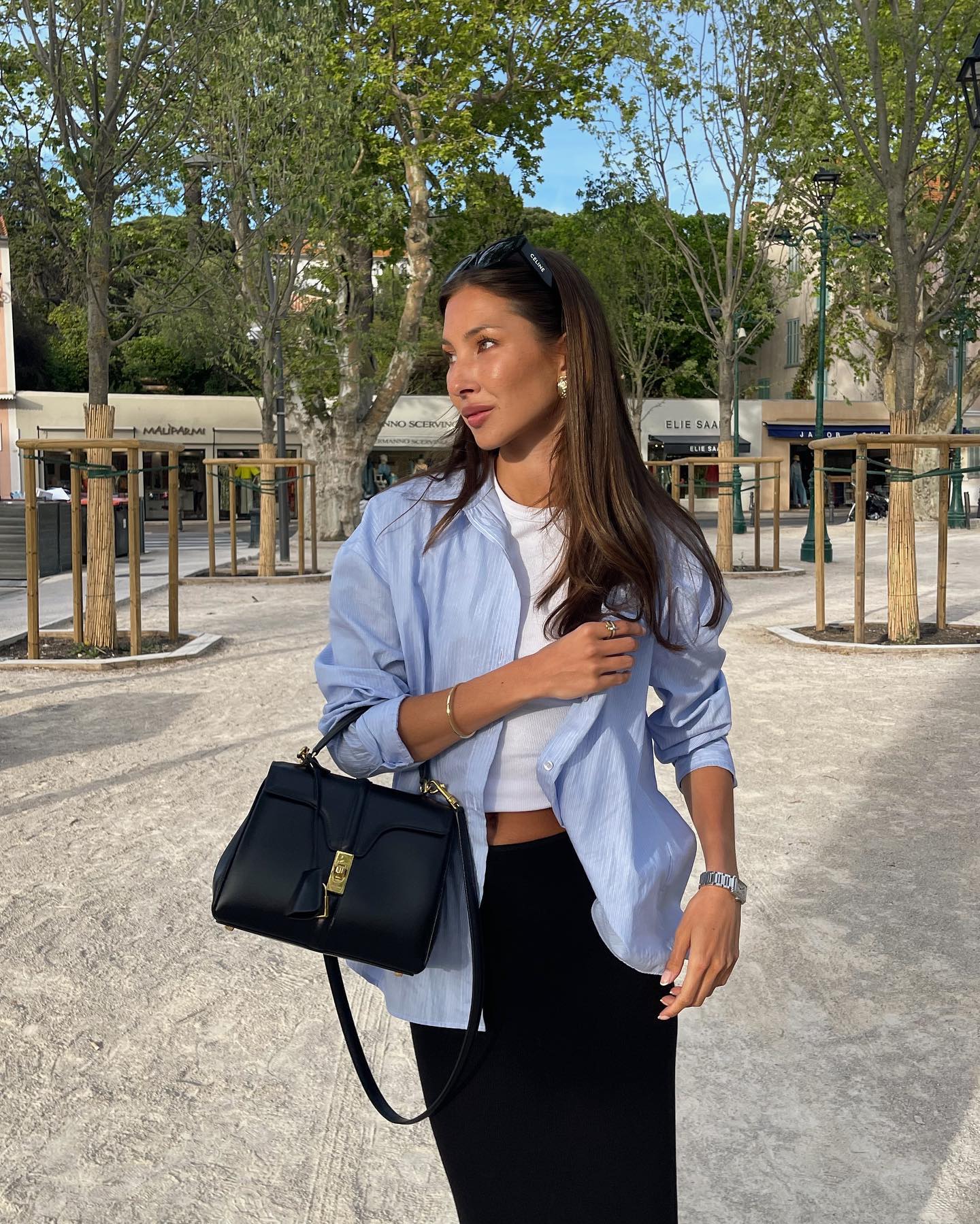 Stylish female influencer Felicia Akerstrom wears a light blue button-down shirt, white t-shirt, and black skirt.