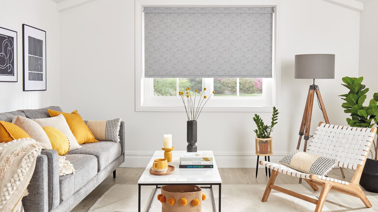 Bright and breezy yellow and grey living room with gray roller blind, and gray sofa with yellow scatter pillows.