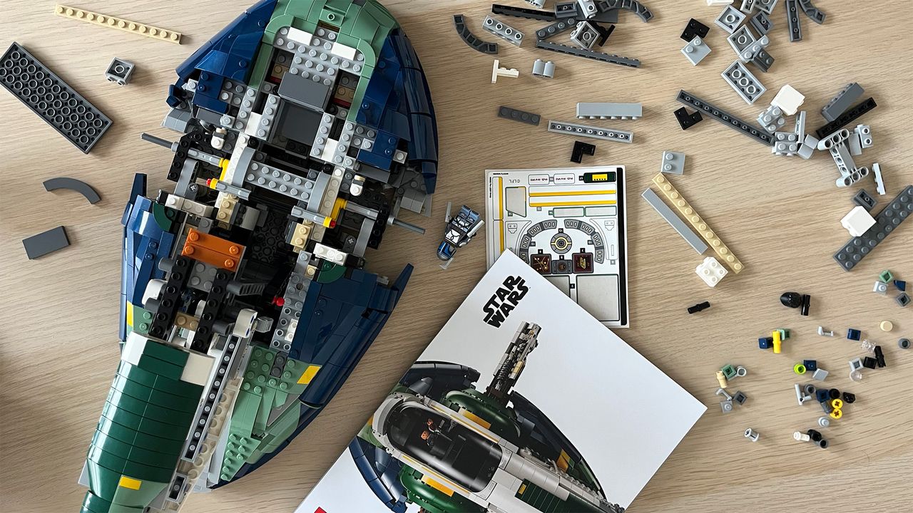 Lego Star Wars UCS Jango Fett&rsquo;s Firespray-Class Starship (75409) mid-build on wooden tabletop next to lots of Lego pieces and an instruction booklet