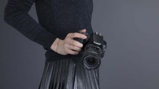 A woman holding the Canon EOS 200D Mark II