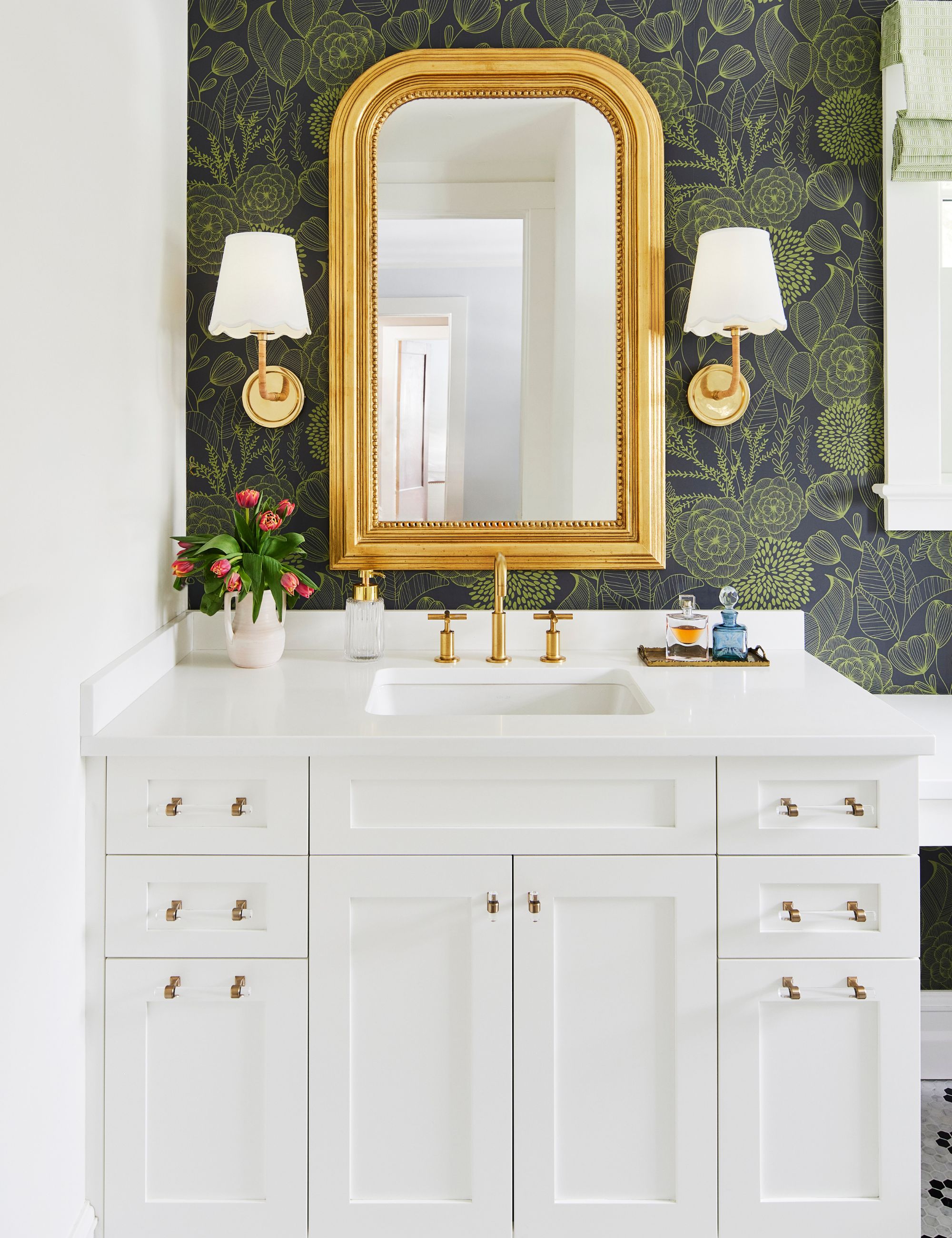 Bathroom with white vanity and gold mirror over the sink and floral green wallpaper