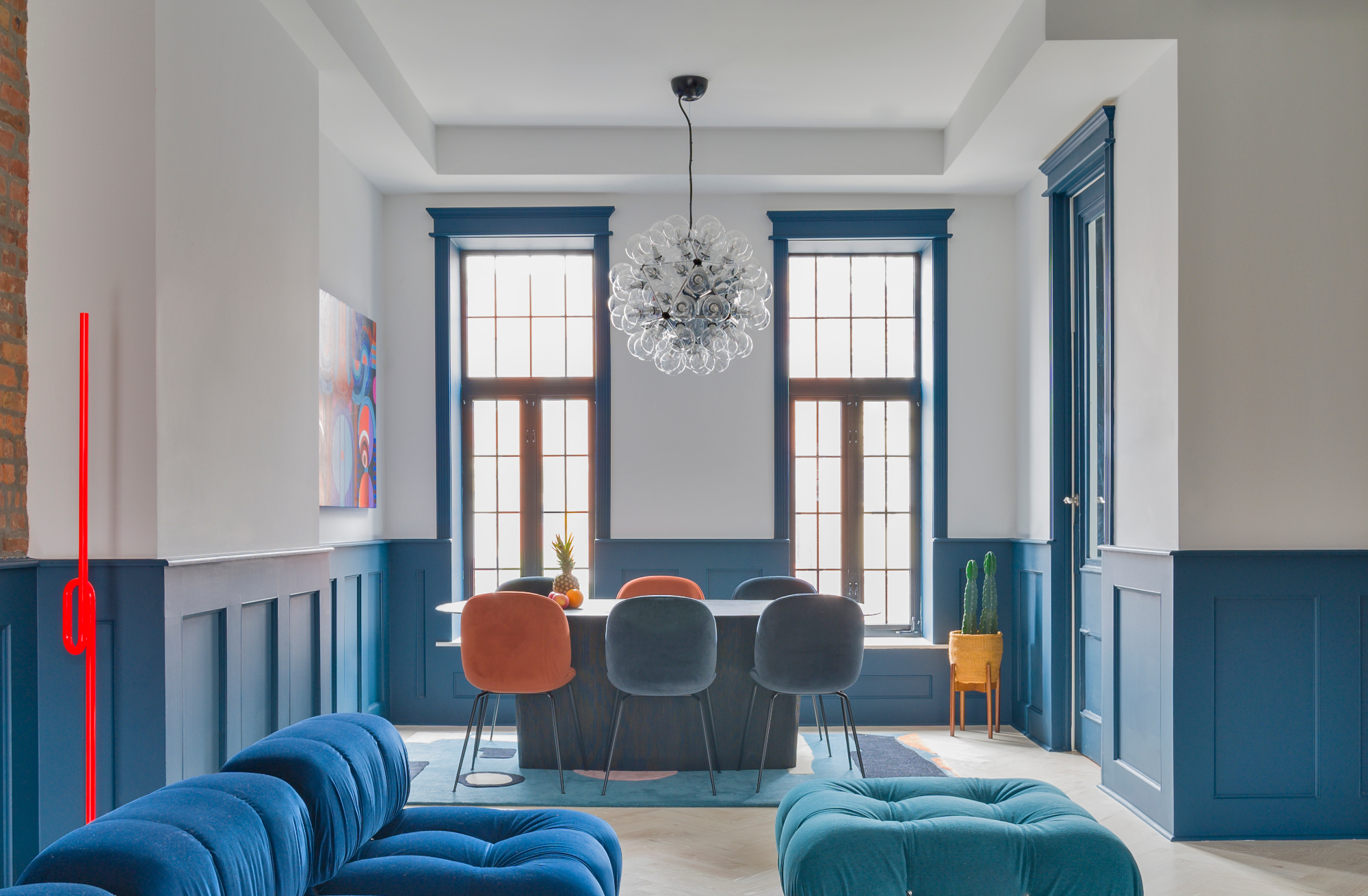 Living-dining room with blue panelled walls and bright blue sofa