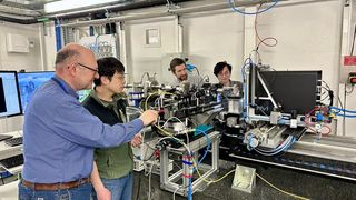 Four scientists gather around a complex piece of machinery in a lab