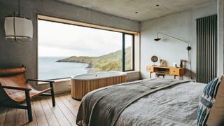 large picture window in bedroom with bath looking out to sea