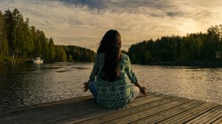 How to relax on Mother's Day: a woman meditates by a lake