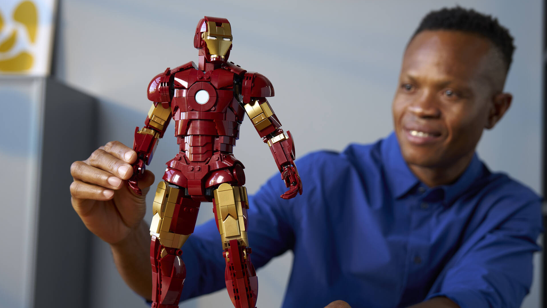 A man poses the Lego Iron Man Mark 3 set