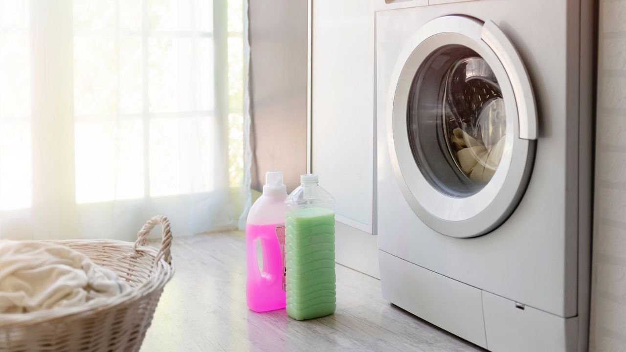 bottles of liquid laundry detergent outside of a washing machine