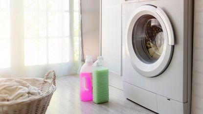 bottles of liquid laundry detergent outside of a washing machine