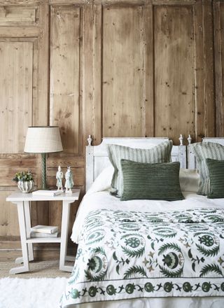 rustic bedroom with wood panelling, white bedside, white painted beds and green bedding