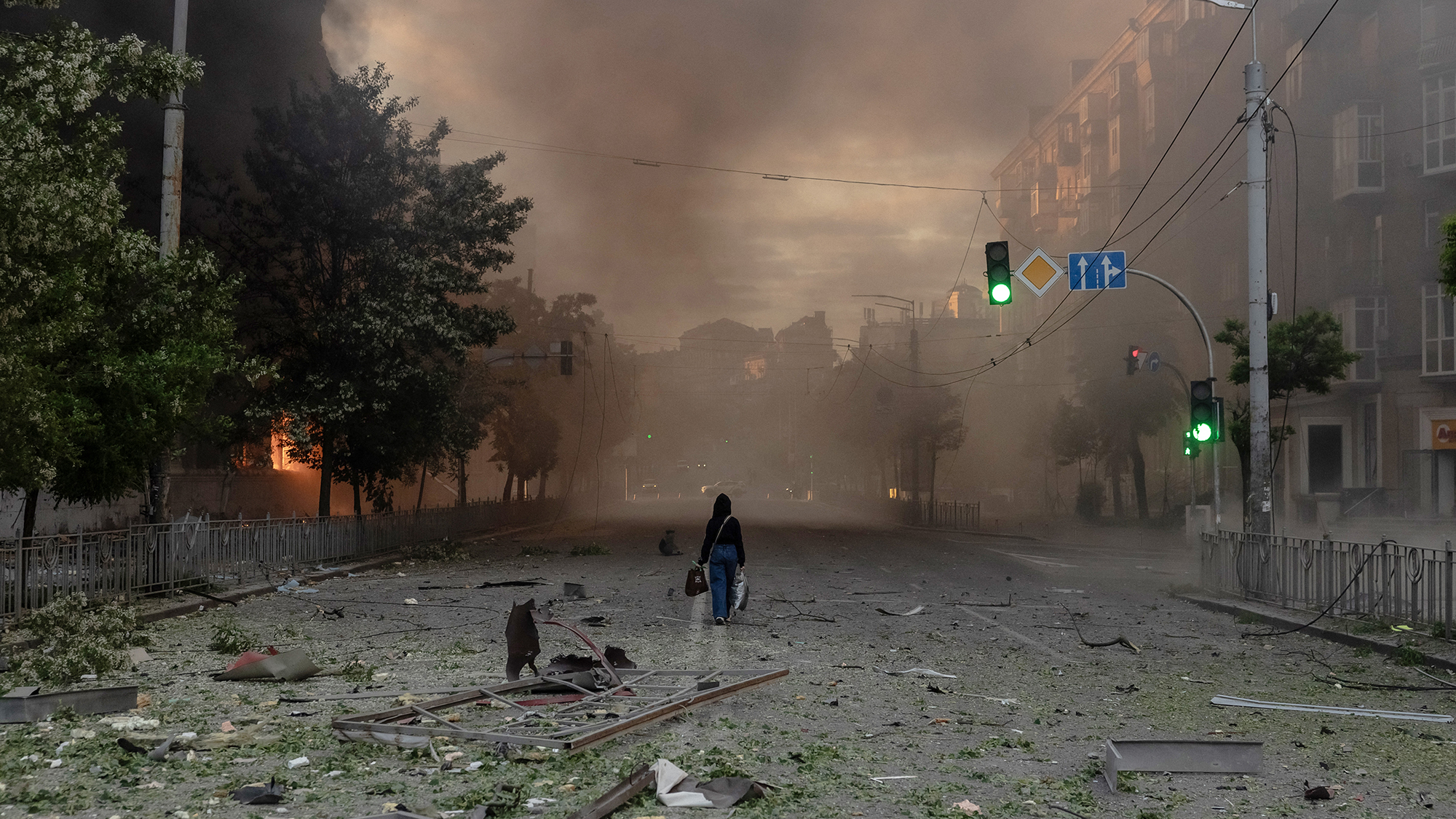 A woman walks through a smoke-filled neighbourhood scattered with debris following intense Russian bombardment, in Kyiv, Ukraine