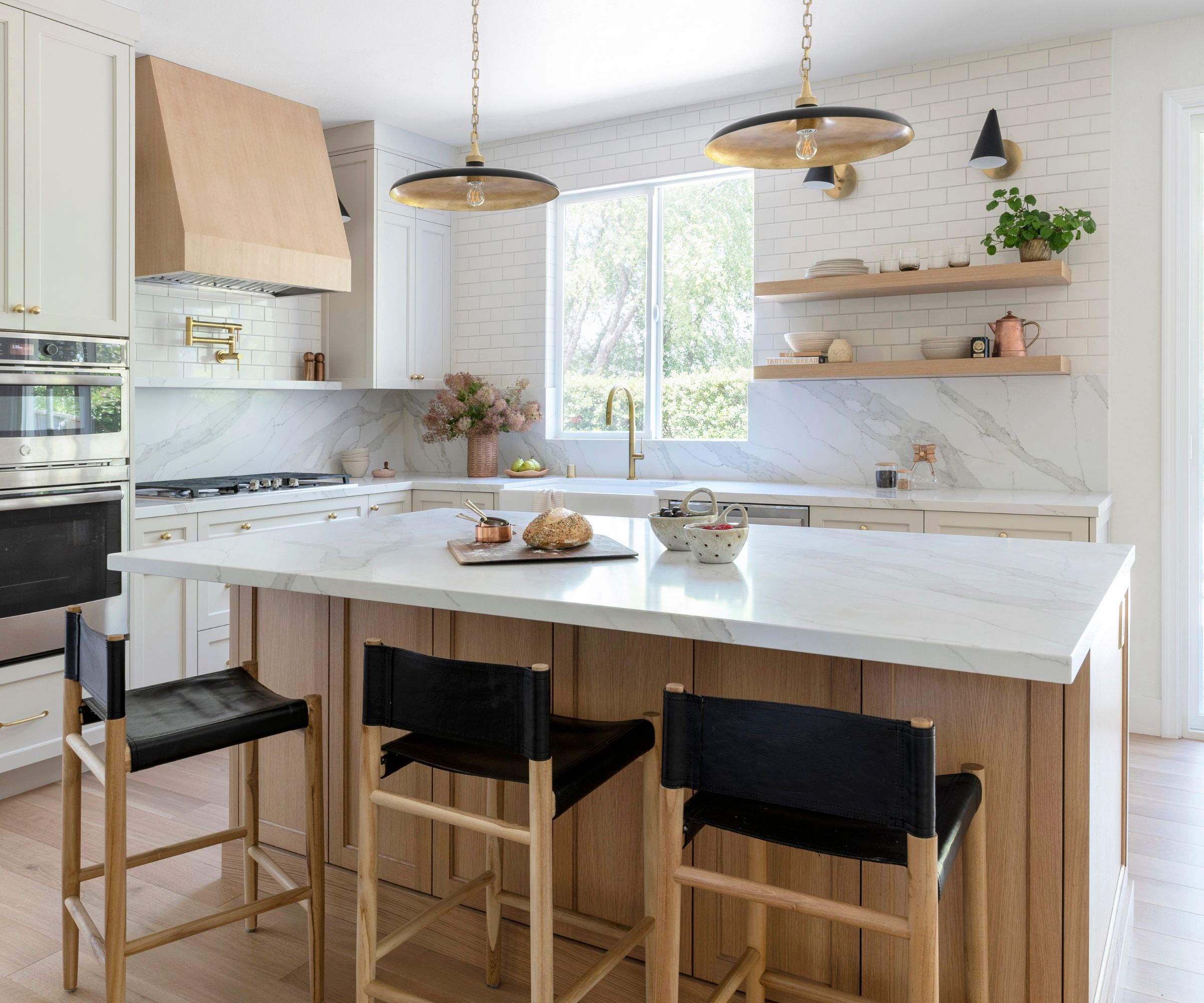 A light kitchen with a mixed material backsplash featuring marble and white subway tiles