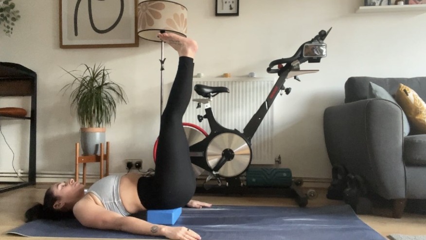 Writer Sam with yoga block supporting lower back performing leg raises