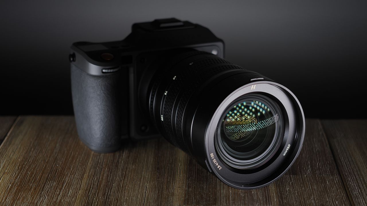 Hasselblad XCD 35-100E lens on a wooden surface in a moodily lit environment