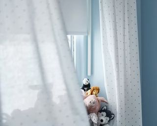 White curtains billowing in breeze of blue kid's room