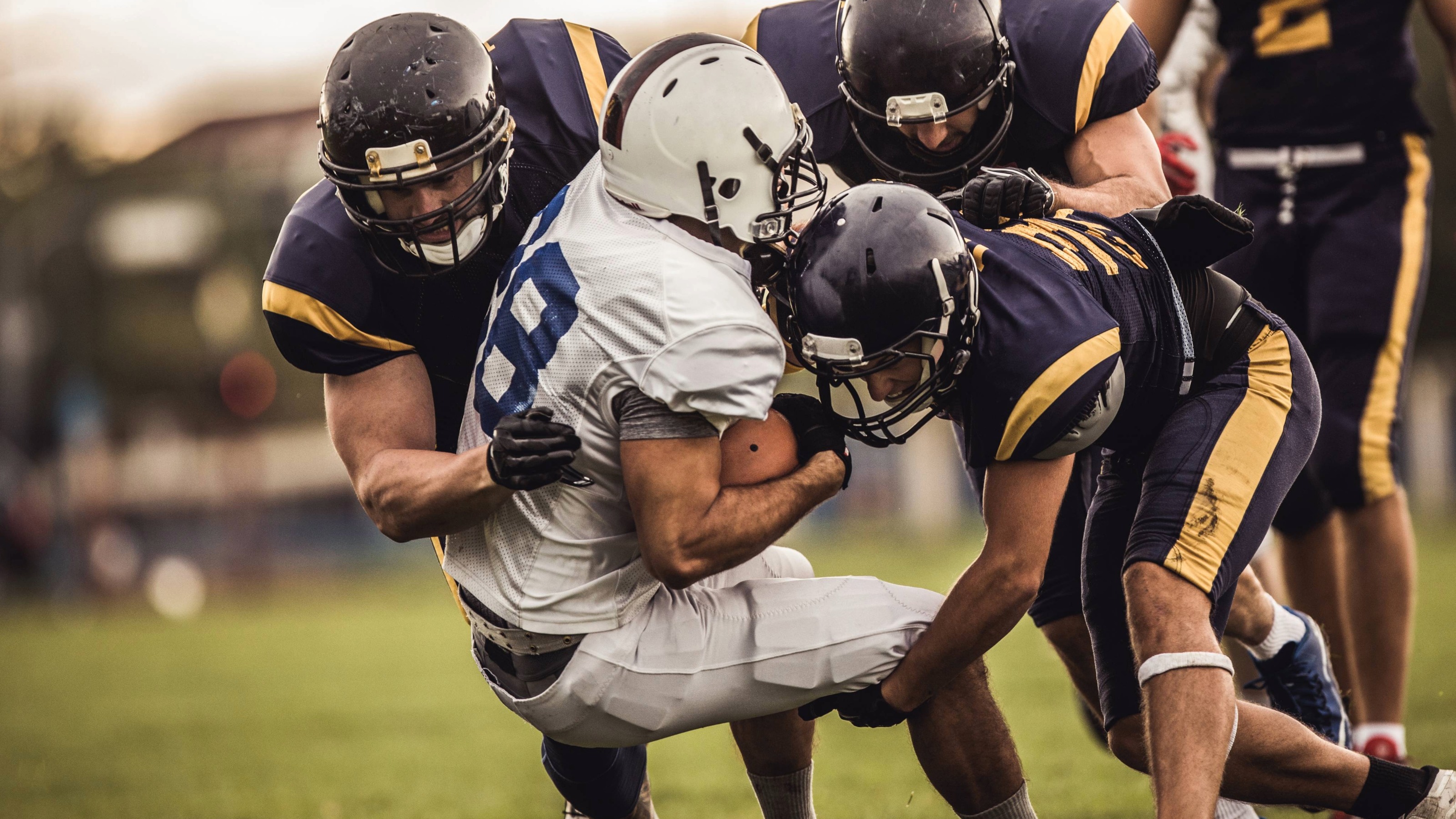 American football players tackling opposite's team quarterback during a match