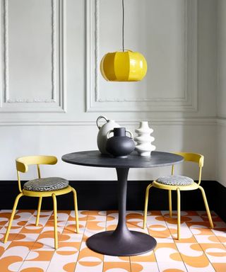 Dining room with black table, yellow chairs, wall paneling and geometric painted floor