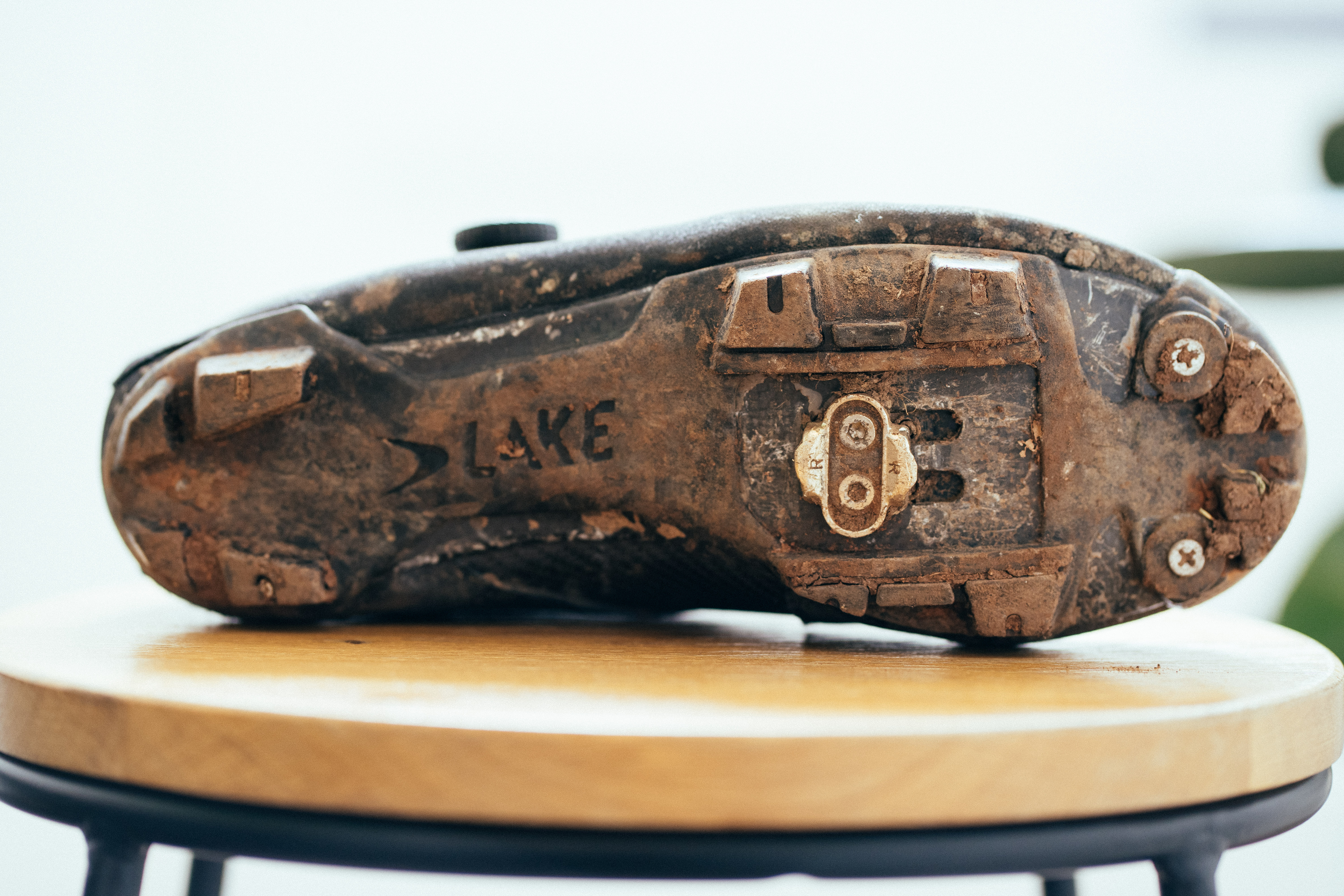 The muddy sole of a black gravel shoe on a wooden stool