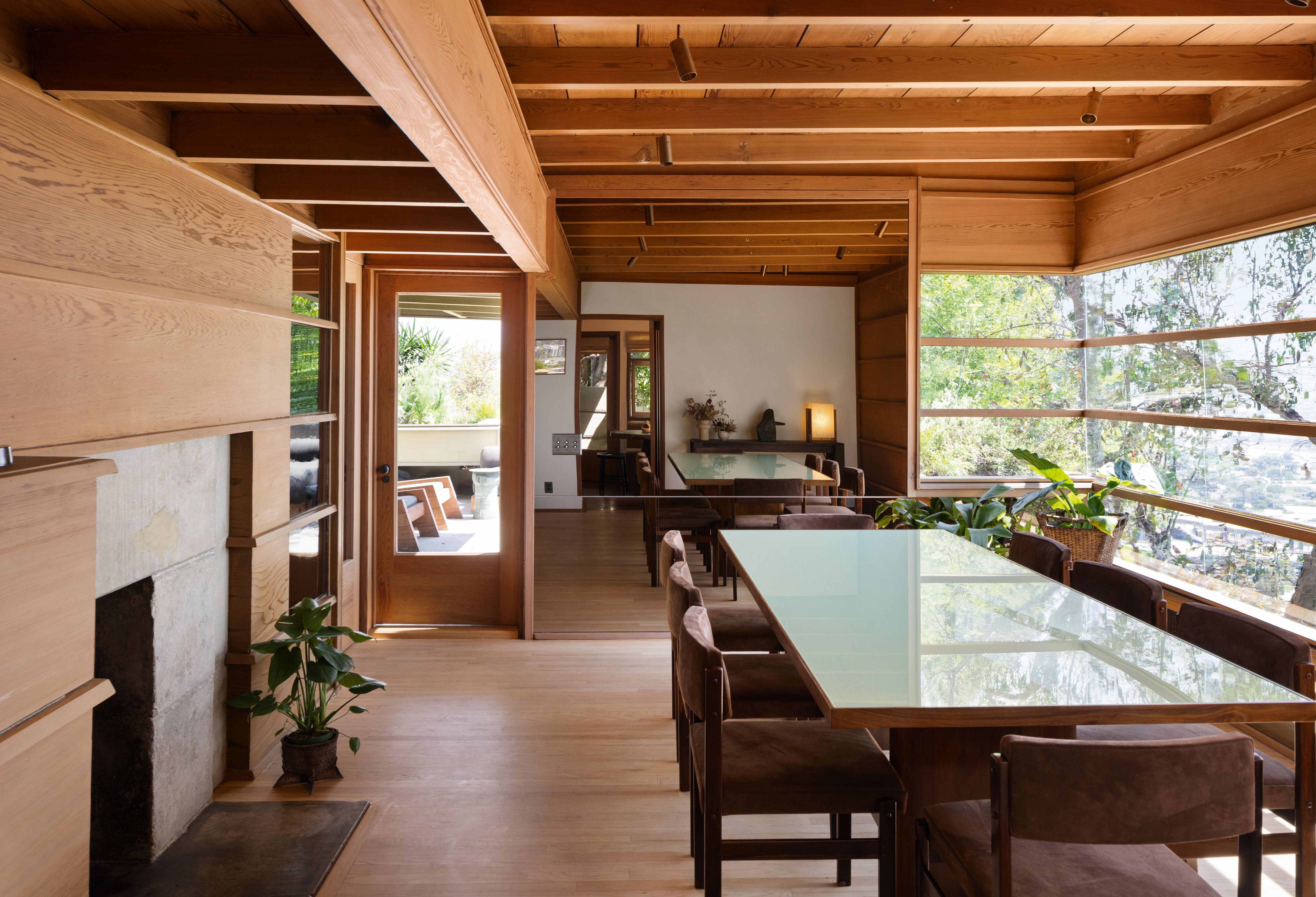 How house’s sparse furnishings include a vintage dining table and reupholstered chairs in a cantilevered room offering a view of the garden