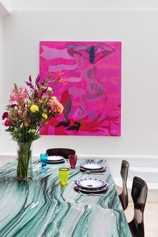 Marble finish decorated table with vase and flowers and bright pink painting of woman on wall