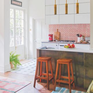 White kitchen with red and white patterned splashback and metallic tile covered island