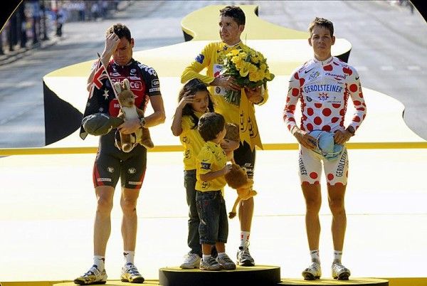 The riders listen to the Spanish national anthem.