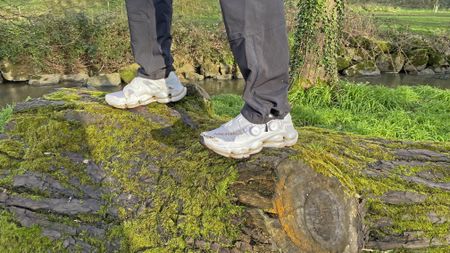 Man wearing Merrell SpeedArc Surge Boa walking shoes, stood on a large log