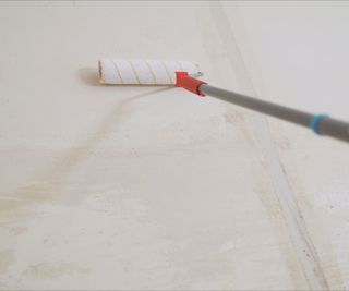 Extendable roller applying primer to wall