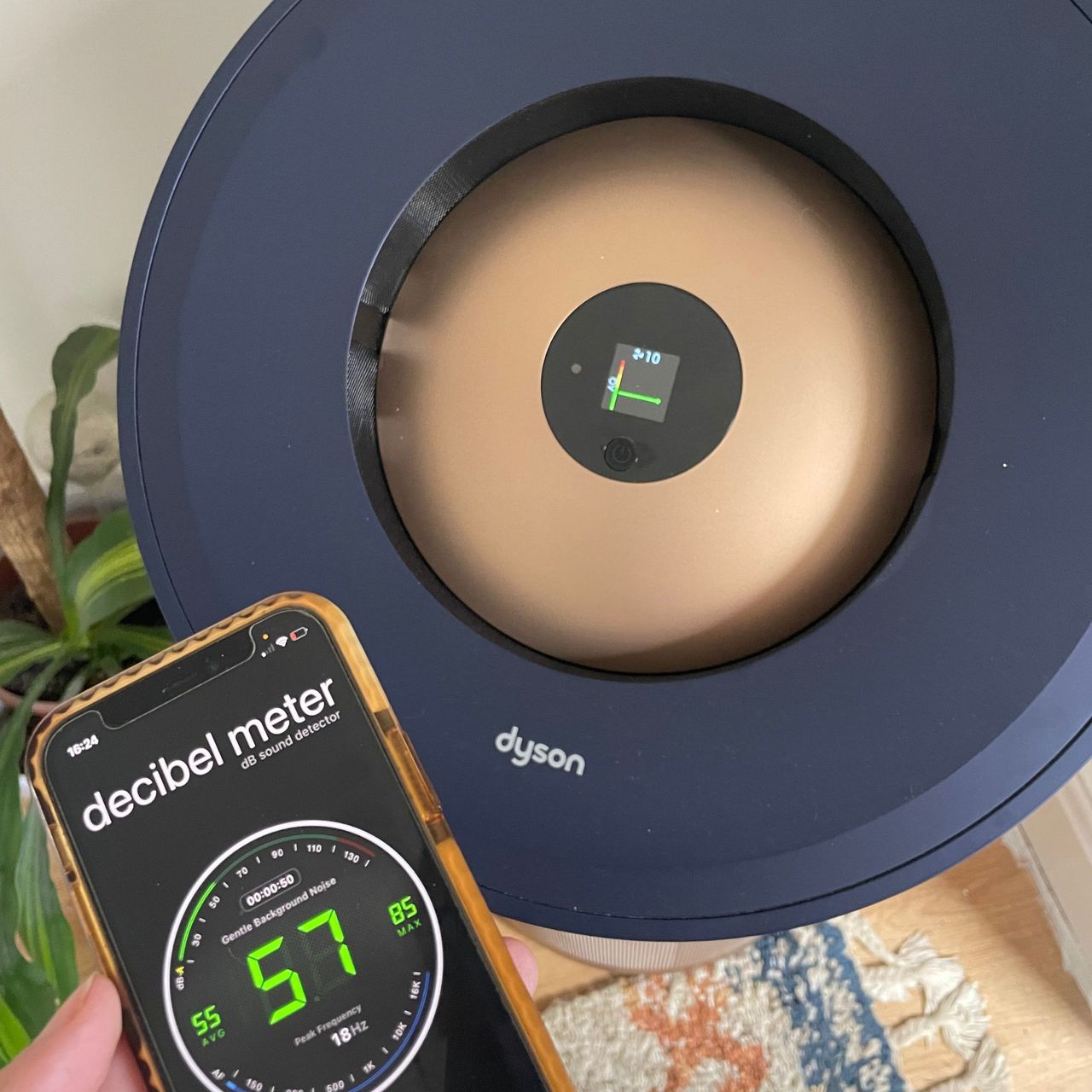 Hand holding phone with a decibel meter app in front of the Dyson Big+Quiet