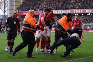 A Leicester fan is dragged away by stewards from celebrating Nottingham Forest players